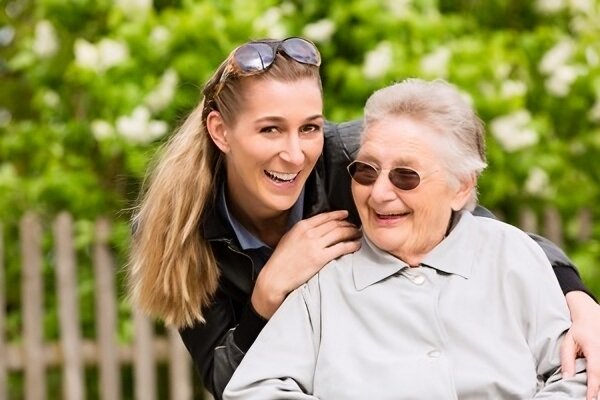 A female occupational therapist joyfully interacting with an elderly woman in a wheelchair, emphasising support and care in mobility and daily activities.